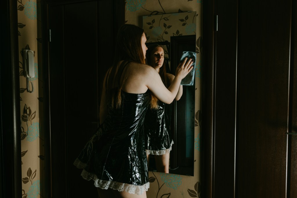 A sexy woman in a French maid cleans a mirror. Adult role play submission games.