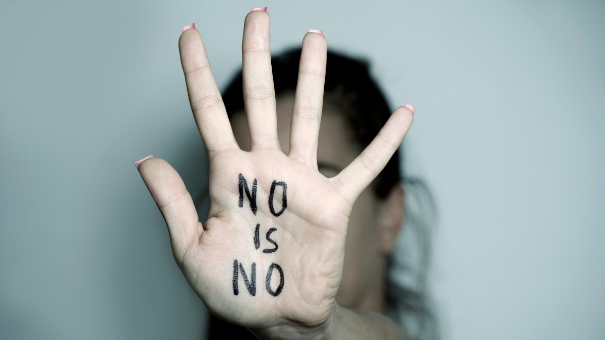 A wioman holds up her hand, writing on her hand reads "no is no", suggests a lack of consent in relationships