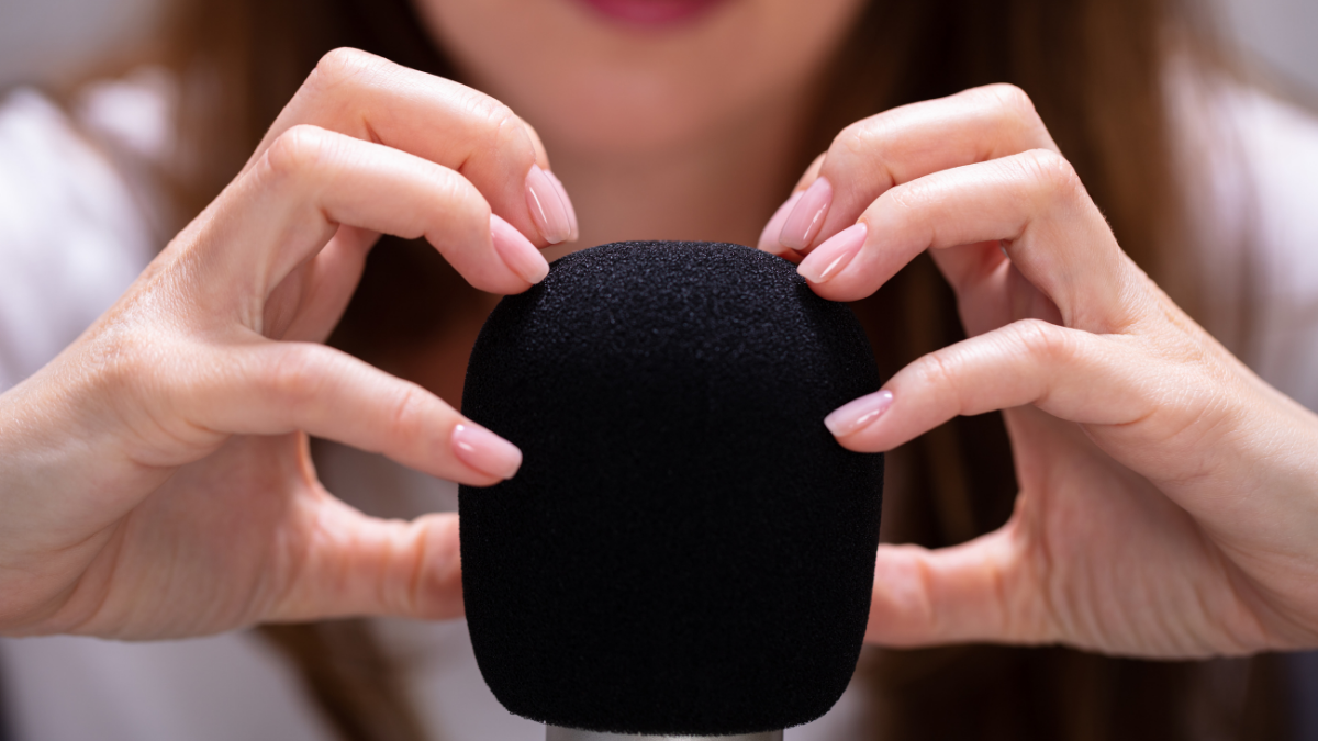 A woman runs her fingers over a microphone to make sounds for ASMR videos