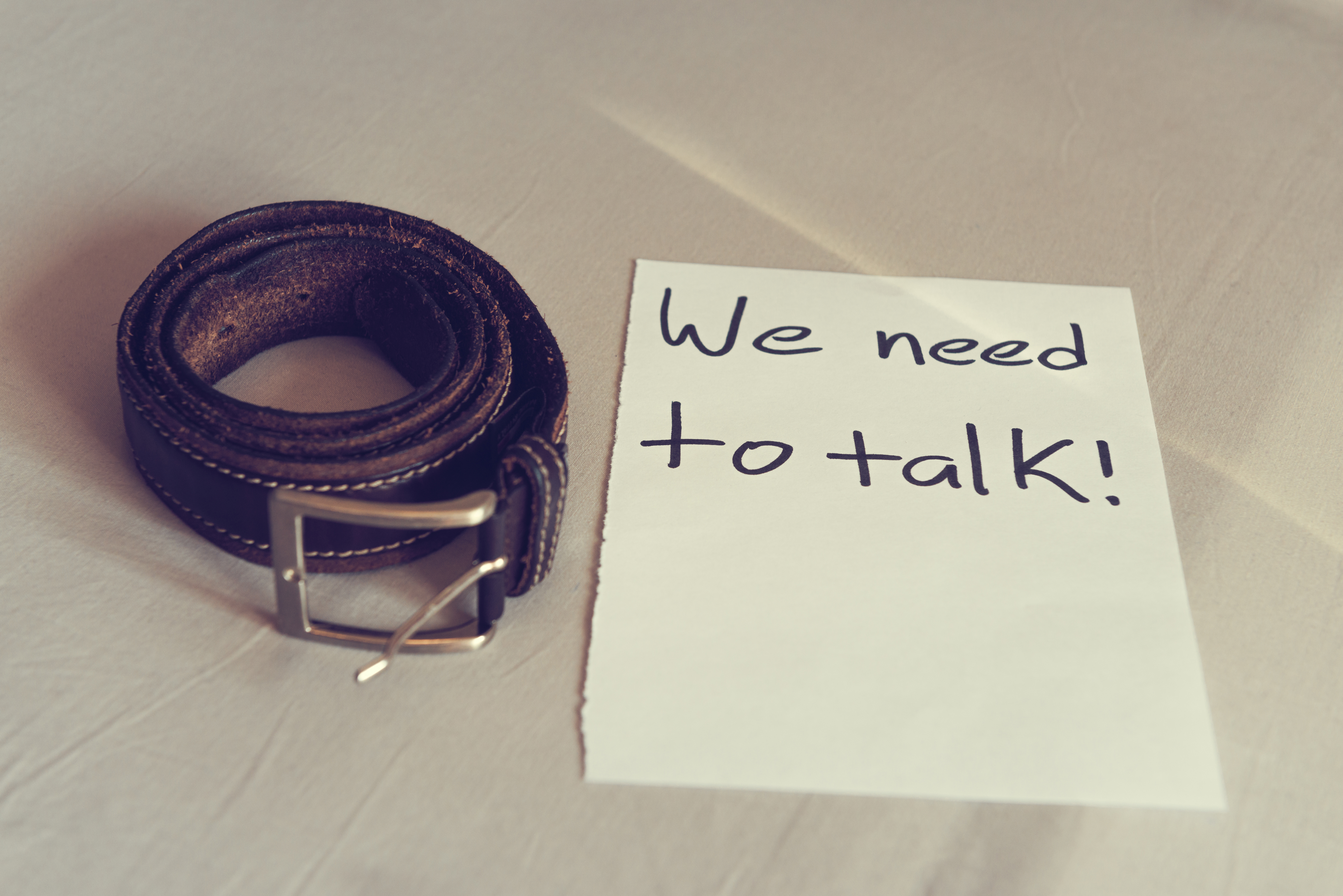 A leather belt next to a note, note reads "weed need to talk", suggests belting bdsm adult games