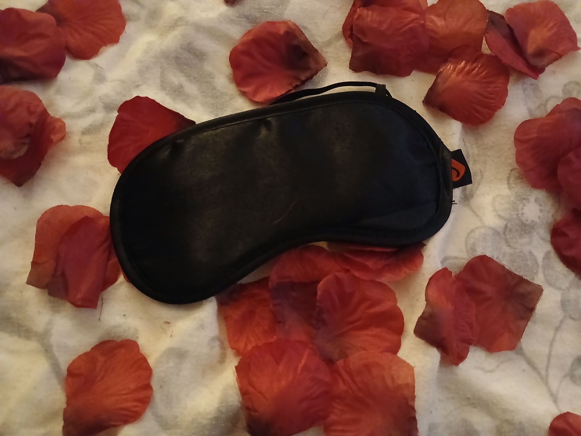 Lovehoney Oh! Satin blindfold in black on a bed of rose petals