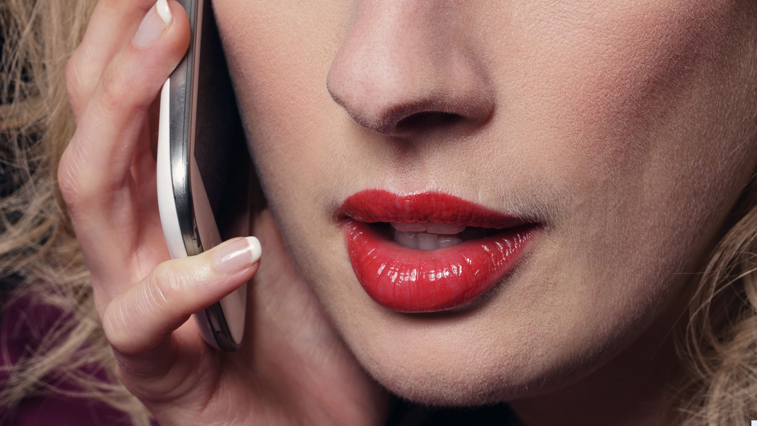 A sexy woman wearing red lipstick talks on a mobile phonr