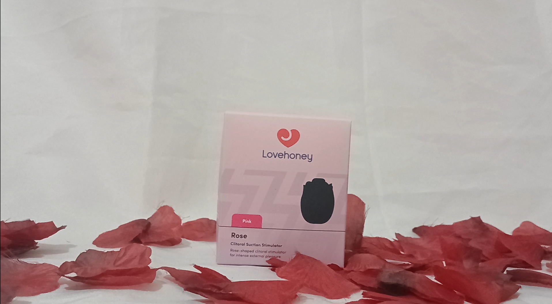 Lovehoney rose clitoral suction stimulator box on red rose petals and a white sheet